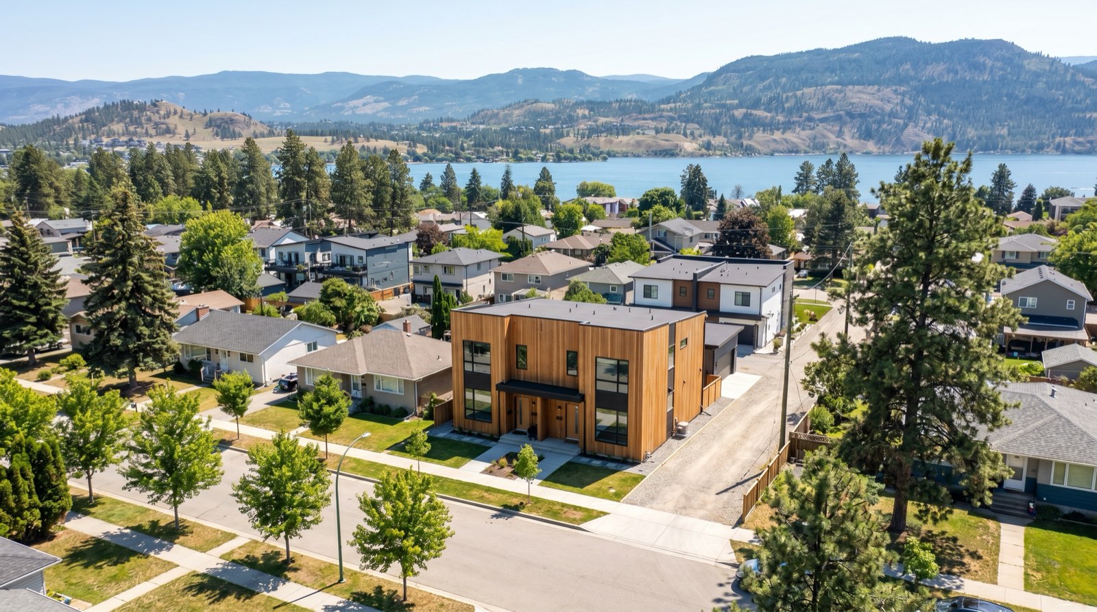 Aerial illustration of Okanagan Lake and the City of Kelowna with ground-oriented infill multiplexes distributed across Core Area neighbourhoods